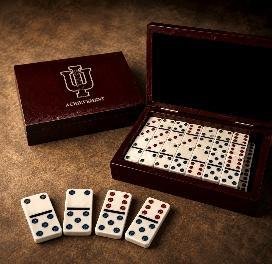 Rosewood case with an engraved lid open to show a double-twelves domino set, several dominoes laid out in front