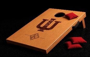 Mini wood bag toss board engraved with Greek letters, with red toss bags beside it